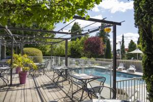 a patio with tables and chairs next to a swimming pool at Campanile PRIME - Troyes Nord Barberey in Troyes