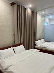 a bedroom with two beds and a window at Huỳnh Thảo in Vũng Liêm