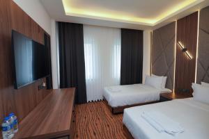 a hotel room with two beds and a flat screen tv at Hotel Global Palace in Haskovo