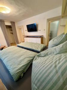 two beds in a room with a tv on the wall at Haus Anna in Köttwein