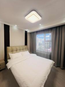 a bedroom with a large white bed with a window at Och Service Apartment in Ulaanbaatar