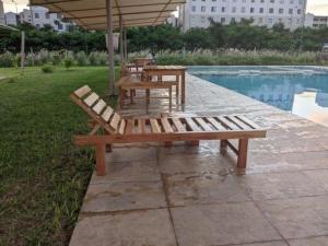 a group of tables and benches next to a pool at 1brm,2bdrm,3bdrm Palm Ridge Heavens Vipingo in Kilifi +8 photos