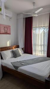 a bedroom with a large bed with a window at 1brm,2bdrm,3bdrm Palm Ridge Heavens Vipingo in Kilifi