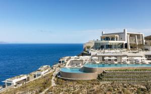 a building with a swimming pool next to the ocean at One&Only Kéa Island in Pisses