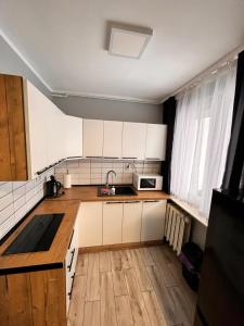 a kitchen with white cabinets and a wooden floor at Apartament Central Wałcz Residence in Wałcz