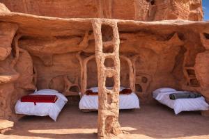 a room with three beds in a cave at Wadi Rum Cave Camping in Wadi Rum