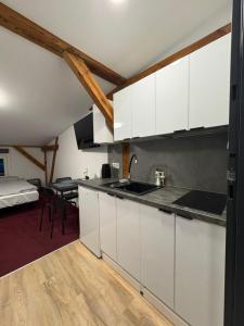 a kitchen with white cabinets and a bed in a room at Apartamenty Stary Młyn in Wronki