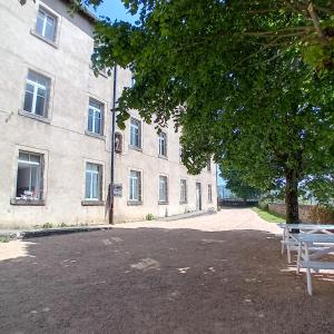 a building with a tree and a bench in front of it at Gîte et Chambres d'hôtes du Musée Ecole in Le Monastier sur Gazeille