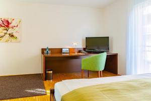 a bedroom with a desk with a bed and a green chair at ACANTUS Hotel in Weisendorf