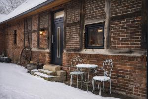 a brick house with two chairs and a door at Lysholm Living Luttmersen Ferienwohnung in Neustadt am Rübenberge