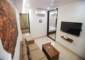 a living room with a couch and a tv on a wall at Suncrisp Studio Rooms in Pedda Waltair
