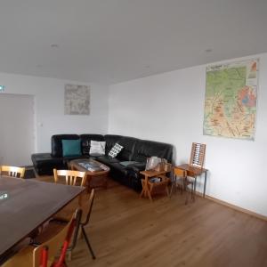 a living room with a black leather couch and tables at Gîte et Chambres d'hôtes du Musée Ecole in Le Monastier sur Gazeille