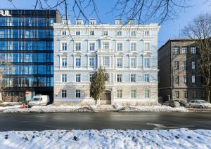a large white building with snow in front of it at Luxury Central Riga Studio, Raina Nams in Riga
