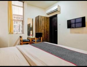 a bedroom with a bed and a desk and a tv at Hotel MNG The Platinum in Kānpur