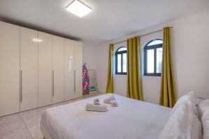 a bedroom with a white bed with yellow curtains at Budget Friendly apartment in Central Swieqi - 10 minutes walk to Paceville & the beach in St. Julianʼs