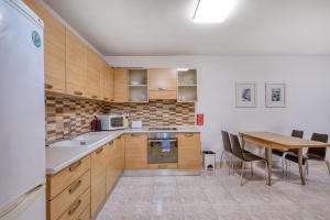 a kitchen with wooden cabinets and a table with chairs at Budget Friendly apartment in Central Swieqi - 10 minutes walk to Paceville & the beach in St. Julianʼs