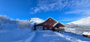 a red barn in the snow with a car parked in front at Røisheim in Tyinkrysset