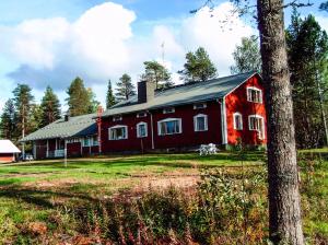 a red barn in a field next to a tree at Kätkävaara Wilderness Lodge in Muurola