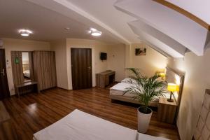 a bedroom with a bed and a potted plant at Zajazd Pod Borem in Pokój