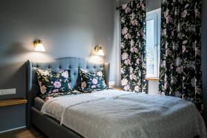 a bedroom with a large bed with floral curtains at River apartamentai in Druskininkai