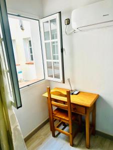 a wooden table and chair in a small room with a window at Hostal Cala Verde in Villaricos