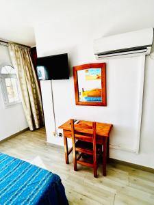 a room with a desk and a bed and a painting at Hostal Cala Verde in Villaricos