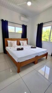 a bedroom with a large bed with blue curtains at Trwa Koko Self-catering in Grand'Anse Praslin +37 photos