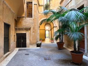 an alley with two palm trees in a building at HiSuiteROME - ApartHotel in Rome