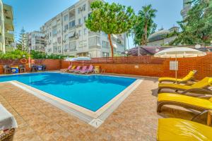 a swimming pool with chairs and umbrellas next to a building at Cleopatra Ada Apart & Suites Hotel in Alanya