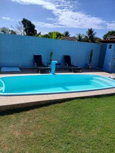 a large blue swimming pool with chairs in a yard at Casa de praia em Barra do Gil in Vera Cruz de Itaparica