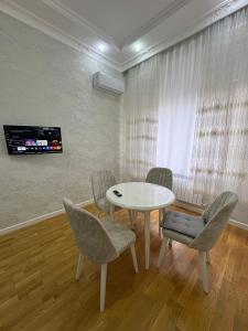 a dining room with a white table and chairs at Caspian Residence in Sumqayıt