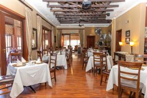 a dining room with white tables and chairs at Premier Hotel Anta Boga in Bloemfontein