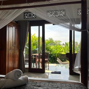 a bedroom with a bed with a view of a patio at Bhakti Ubud Villa in Ubud