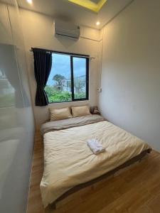 a small bed in a room with a window at Lunara Homestay in Phú Vang