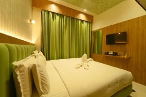 a bedroom with a white bed with a green curtain at Yuvraj Land Mark in Mysore +80 photos