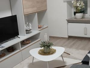 a white living room with a table and a tv at Meri per sempre in Pontebba