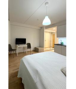 a bedroom with a white bed and a kitchen at LuxHOMES Studio in Tapiola in Espoo
