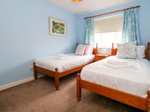 two beds in a room with blue walls and a window at Still Waters in Wyke Regis