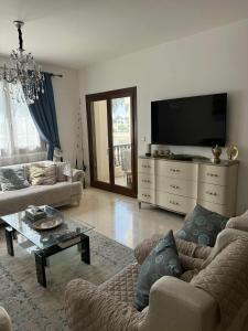 a living room with two couches and a flat screen tv at Dream Apartment in Salalah