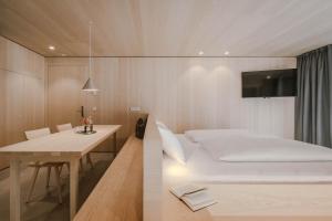 a small bedroom with a bed and a table at Kersh Dolomites Lodge in San Candido