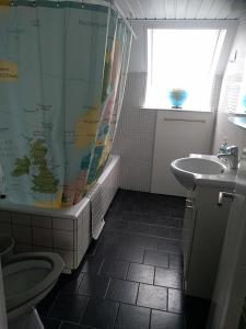 a bathroom with a sink and a toilet and a shower curtain at Skolevænget 35 in Skjern +7 photos