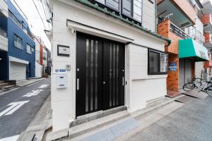 a white building with a black door on a street at NISHIKI Ryokan錦旅館 in Tokyo