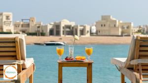 a table with two glasses of orange juice and a flower at Heated Pool 4BR Villa, Lagoon Front, Ancient Sands - OllyStays in El Gouna +24 photos