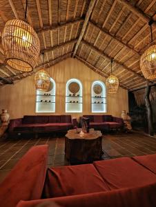 a room with red couches and a table and chandeliers at Gaga Bees Udawalawe in Udawalawe +59 photos