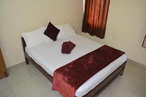 una camera da letto con un letto con un accappatoio rosso sopra di JP Nivaas Guest House a Mayiladuthurai