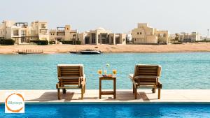 two chairs and a table next to a swimming pool at Heated Pool 4BR Villa, Lagoon Front, Ancient Sands - OllyStays in El Gouna