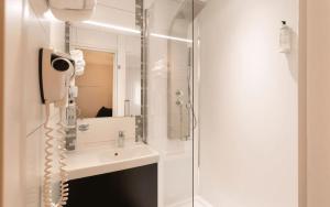 a white bathroom with a sink and a shower at Logis Hotel Restaurant Au Chêne Vert, Saint-Brieuc in Plérin