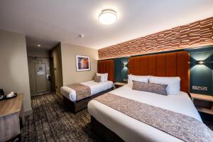 a hotel room with two beds and a wall at The Maiden City Hotel in Derry Londonderry +55 photos