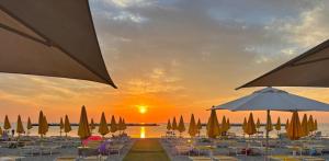 a group of umbrellas and chairs with the sunset in the background at Casa Mia - Lido Adriano by Ferket Holiday Rentals in Lido Adriano