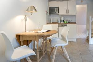 a kitchen with a wooden table and white chairs at Westerhoern 46 Haus 2 App 24 in Keitum
